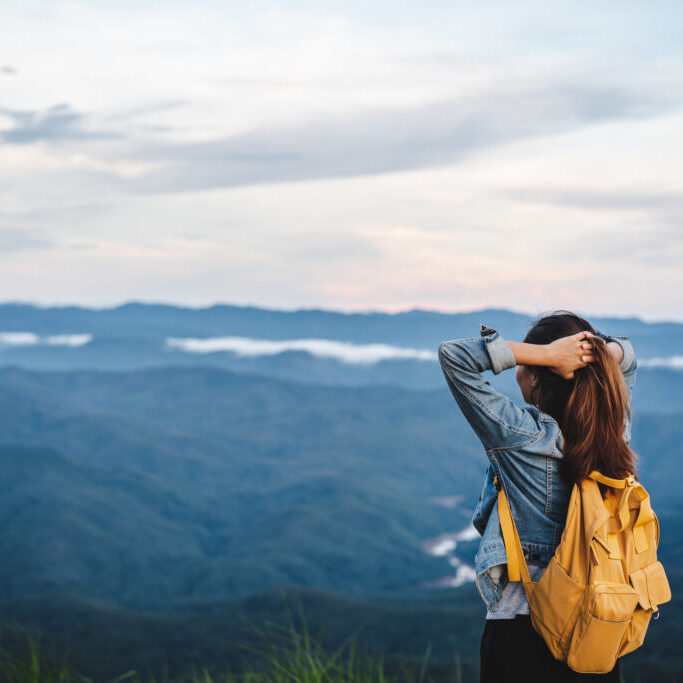 Happy Young Woman Traveler Relaxing And Looking At The Beautiful Sunset On The Top Of Mountain